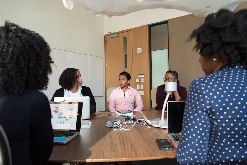 Diverse team of adults collaborating in a meeting room with laptops and documents on the table
